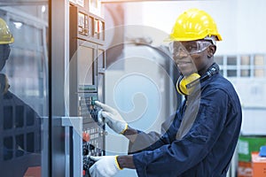 Black man working at programmable machine in factory industries photo