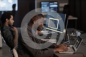 Black man writing code and typing at laptop keyboard