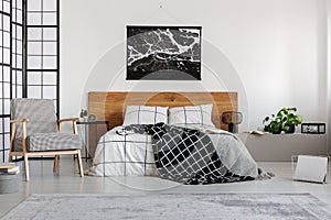 Black map on white wall above wooden headboard in simple bedroom interior photo