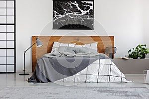 Black map on white wall above wooden headboard in simple bedroom photo