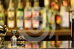 Black marble table top and beautiful bokeh shelves with alcohol bottles
