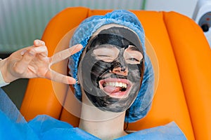 Black mask on girl face for carbon peeling. Dermatology and cosmetology. Using surgical laser.