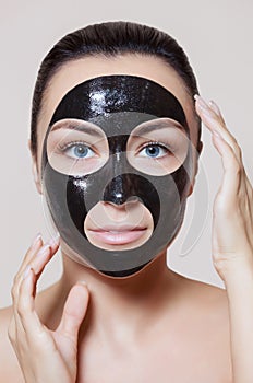 A black mask to the face of a beautiful woman. Spa treatments and care of the cats