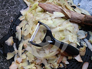 Plastic potato peeler with fresh white potato peelings photo