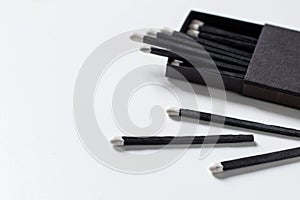 Black matches in matchbox on white background