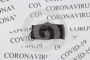 Black medical mask on coronavirus inscriptions background and covid-19. Pollution, virus and flu protection concept. Professional