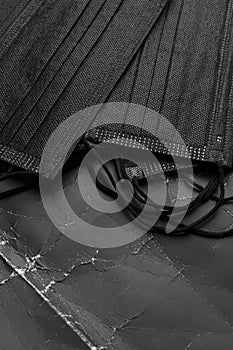 Black medical masks on black crumpled paper with wrinkles and folds