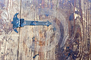 Black, medieval-style iron loop with nails on background of old, stained, cracked, oiled wooden planks, with clear pattern of wood