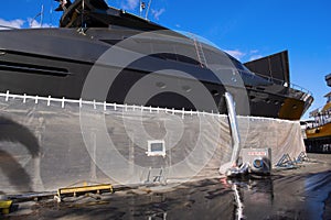 Black mega yacht on the hard at a boat yard with dehumidifier