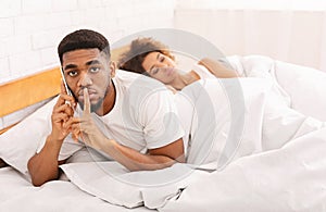 Black man cheater talking privately on cellphone in family bed photo