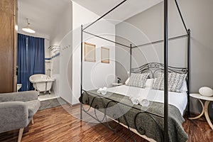 Black metal canopy bed with cushions, en-suite bathroom