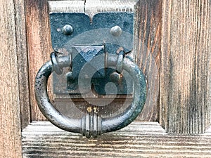Black metal door knocker, door knob with a ring for knocking on the background of a wooden brown old vintage door