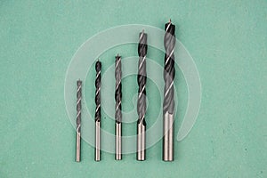 Black metal drill bits on a blue paper background isolated.