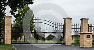 Black metal driveway entrance gates set in fence