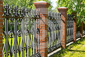 Black metal fence with brick pillars.