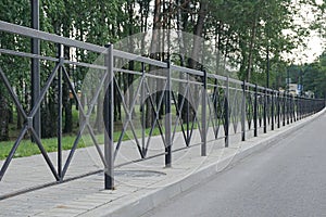 Black metal fence. Iron fence along the road