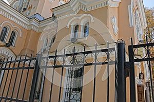 Black metal fence of sharp iron bars in front of the concrete brown wall