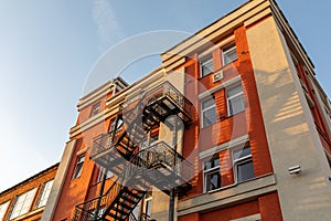 Black metal fire escape on the facade of an old brick building. Security concept, renovation.