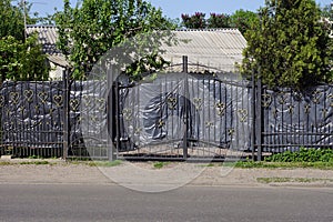 Black metal gate and a door made of iron bars in a wrought iron pattern
