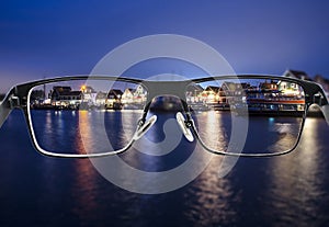 Black metal glasses looking through colorful night cityscape photo