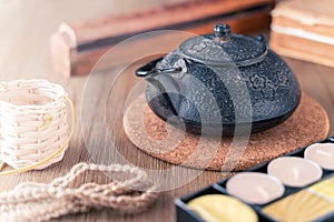 Black metal Japanese tea pot on a wooden table with tea candles and wooden box of fragrant sticks. Zen -style still life