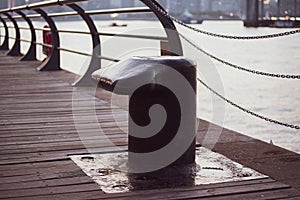 Black metal mooring bollard in marina and port terminal. Close up of mooring noray on a dock photo