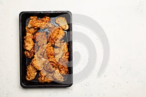 Black metal pan with battered fish or chicken or meat