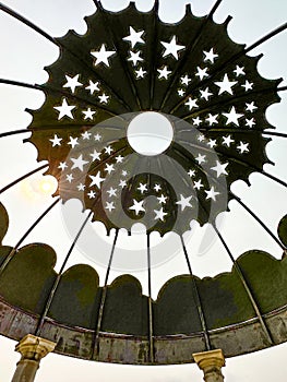 Black metal roof with cut-out star shapes on circular garden gazebo