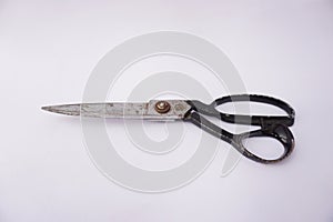 Black metal sewing scissors isolated on white and in vintage style which is slightly rusty.