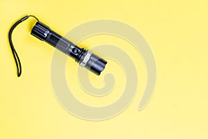 Black metal small tactical falshlight isoltaed on yellow background