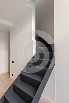 Black metal stairs leading to second floor. Interior of empty renovated apartment in a duplex flat.