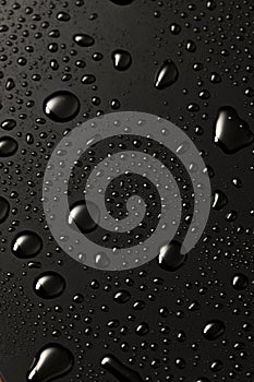 Black metal water drops on dark reflective surface