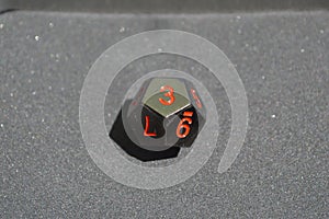 Black metallic d12 twelve sided dice on foam surface