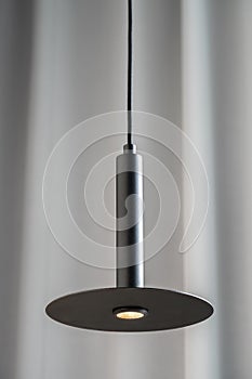 Black metallic lamp hanging on gray curtain background