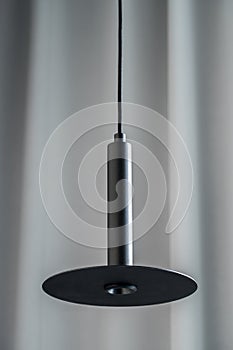 Black metallic lamp hanging on gray curtain background