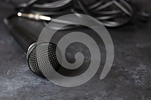 Black microphone on a dark concrete background. Equipment for vocals or interviews or reporting. Copy space