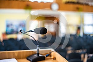 Black microphone in an empty conference hall, empty chair, ready for public speaking.