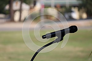 Black microphone mounted on stage, blurred background, selectable focus, event concept.