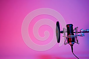 black microphone on pink and purple neon background with copy space