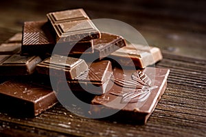 Black and milk chocolate bars dark wooden table background