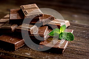 Black and milk chocolate bars with mint dark wooden table background