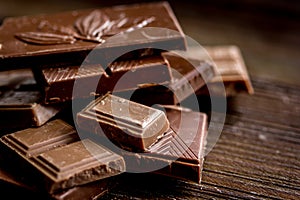 Black and milk chocolate pieces wooden table background