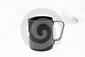 Black milk stainless pitcher object make coffee on white table and fabric background