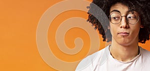 Black millennial man looking skeptically aside at empty space