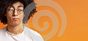 Black millennial man looking skeptically aside at empty space