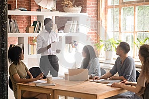 Black millennial man stand talking collaborating with diverse group