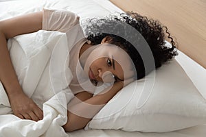 Black millennial woman lying in bed suffering from insomnia