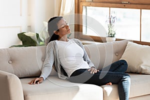 Black millennial woman sit on sofa in living room