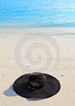 Black millinery from sun ays on sand before ocean