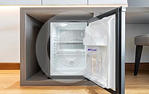 Black mini small fridge refrigerator under the frame wooden counter in hotel resort bedroom